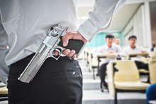 A Lecturer Holding A Gun In His Hand In A Lecture Room / Armed Campus Concept