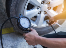 Close Up Mechanic Inflating Tire And Checking Air Pressure With Gauge Pressure      