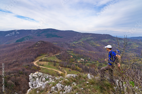 A hiker at the rock watching winding mountain road below, Homolje mountains, eas Poster