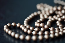 Long Necklace Made Of Brown Beads On A Dark Background 