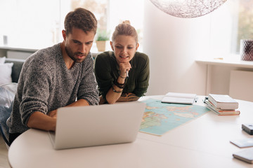 Young couple exploring the world on laptop computer.