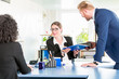 © Kzenon - Man hands over a blue ring binder to his co-worker at the office