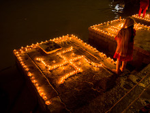 A Woman Stands Next To  Swastika Decoration Of Clay Lamps (diya) In Varanasi (India) On The Festival Of Dev Diwali