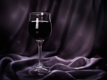 Glass Of Red Wine On Purple Rippled Silk Fabric.