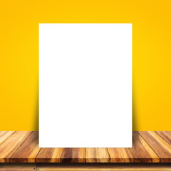 Sticker - White paper poster lean at yellow wall and wood table.