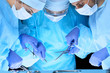 © rogerphoto - Medical team performing operation. Group of surgeons at work in operating theater toned in blue