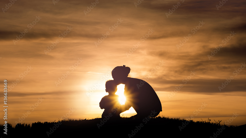 Silhouette of a young mother lovingly kissing her little child o - obrazy, fototapety, plakaty 