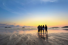 Group Of Happy Young People Look On Beautiful Summer Sunset At The Beach