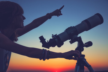 Wall Mural - girl looking at the stars with telescope beside her.