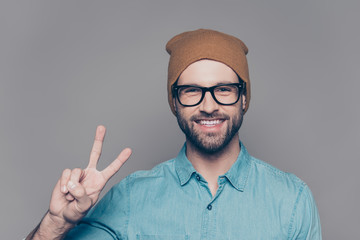 Handsome cheerful man  in hat and glasses showing v-sign