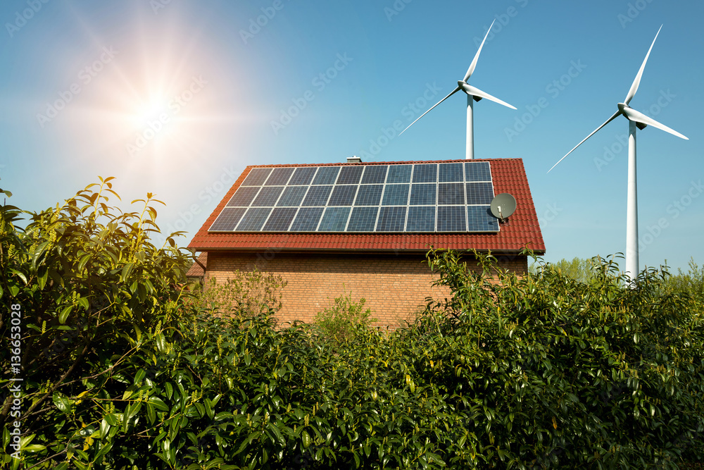 Solar panel on a roof of a house and wind turbins arround - concept of ...