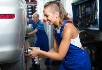 Sticker - woman technician fitting new tires to car at workshop