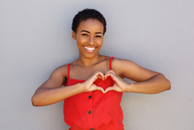 Smiling Young African American Woman With Heart Shape Hand Sign