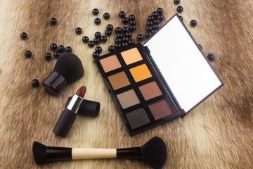 Makeup tools on Fur background / featuring eyeshadow palette, lipstick, makeup brushes on a fury background