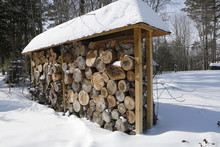 Stack Of Firewood Logs In Bright Winter Day With A Lot Of Snow Around.