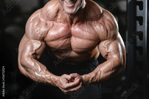 Fotografía Brutal strong bodybuilder man pumping up muscles and train gym