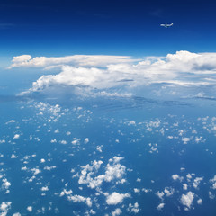 Oncoming flight traffic in mid air. Aircraft flying above ocean, beautiful white cloud. Clear blue sky, aerial view from cabin through plane window. Vacation tour, travel background with copy space