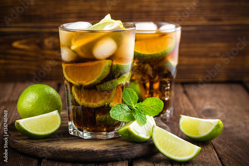Photo Cuba Libre cocktail with cola, lime and ice in glass, cold longdrink