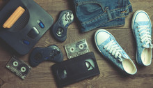 Back In The 90s. Shoes, Audio Tapes, Video Tapes, Game Console, Jeans. Top View. Flat Lat.