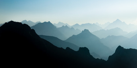 Spectacular blue and cyan mountain ranges silhouettes. Summit crosses visible.