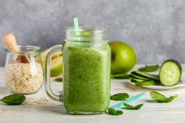 Wall Mural - Fresh green smoothie from fruit and vegetables for a healthy lifestyle and ingredients for making dietary drink (spinach, green Apple, cucumber, oatmeal)
