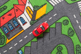 Red toy car on a city themed carpet, city street concept