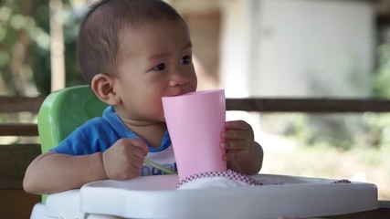 Wall Mural - 10 months Asian baby drinks water by himself
