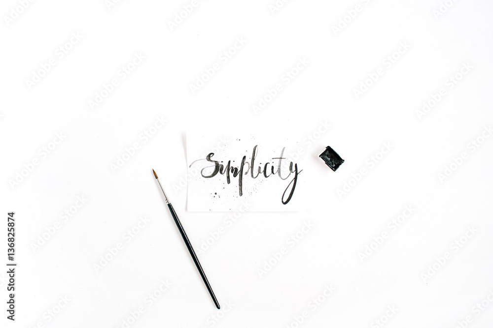 Minimalistic stylish composition with word Simplicity written in calligraphic style on paper with paint brush on white background. Flat lay, top view - obrazy, fototapety, plakaty 
