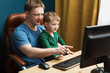 © ulza - Father and little son using  computer at home. The father with the son watch video and cheerfully spend time together. Stady in the computer.