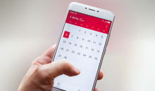 Hand with a smartphone with a calendar, one month plans