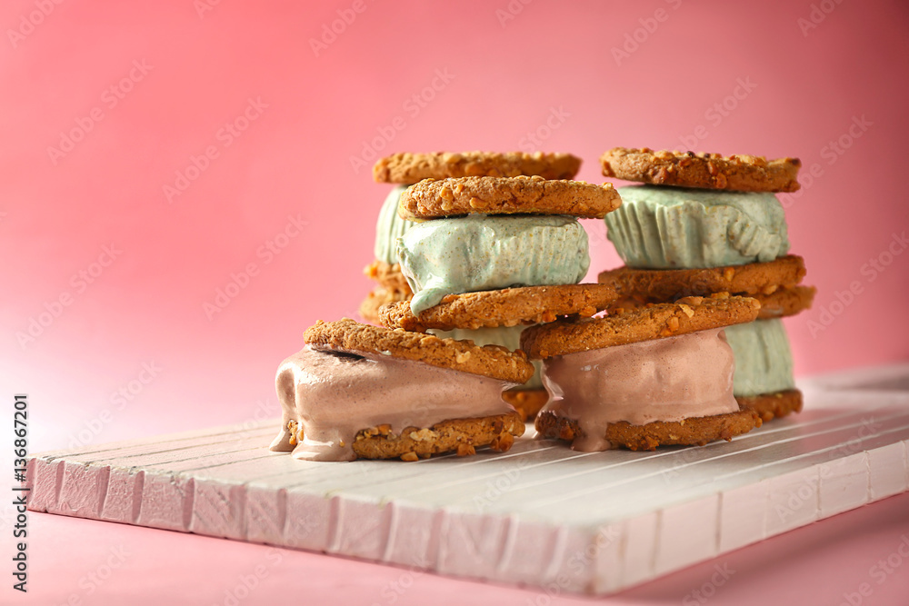 Delicious kiwi and chocolate ice cream cookie sandwiches on white wooden board and pink background