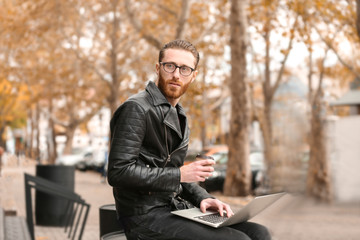 Handsome young man working on laptop outdoors