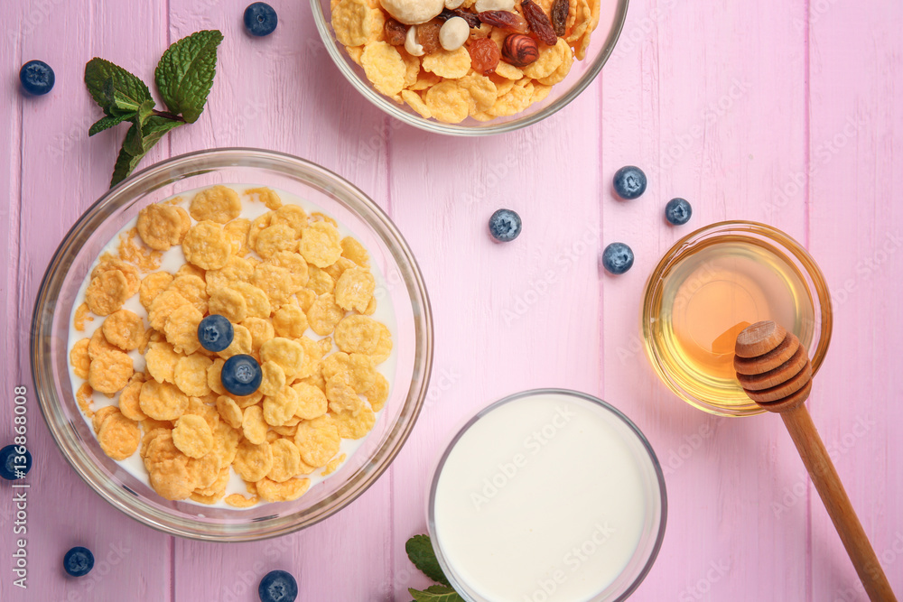 Tasty cornflakes with blueberries,nuts and raisins on pink background