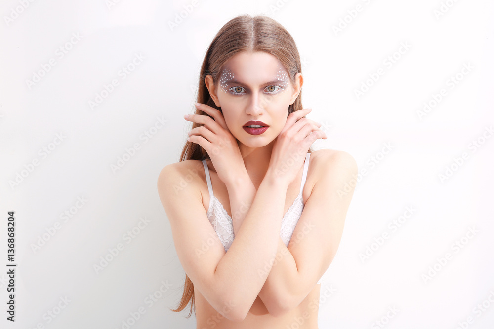 Young model with creative makeup on white background