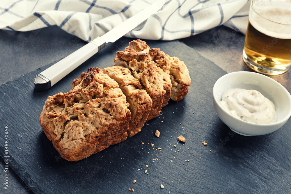 Slate plate with tasty loaf of beer bread on table