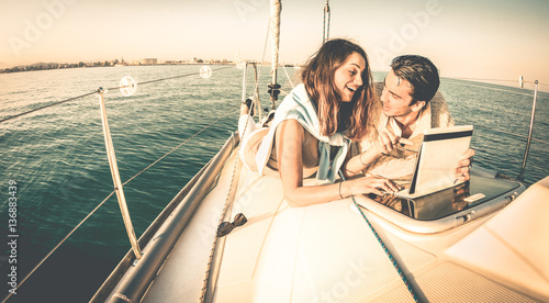 Young Couple In Love On Sail Boat Having Fun With Tablet Happy