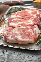 Poster - Three raw pork steaks on iron tray on light surface