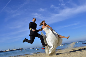 Wall Mural - Pareja de recién casados saltando en la playa.