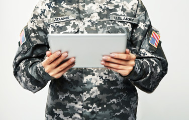 Wall Mural - Female soldier with tablet computer on grey background, closeup