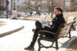 © Drobot Dean - Happy relaxed young man reading newspaper on the bench outdoors
