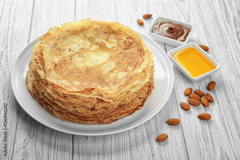 Plate with tasty pancakes on white wooden table