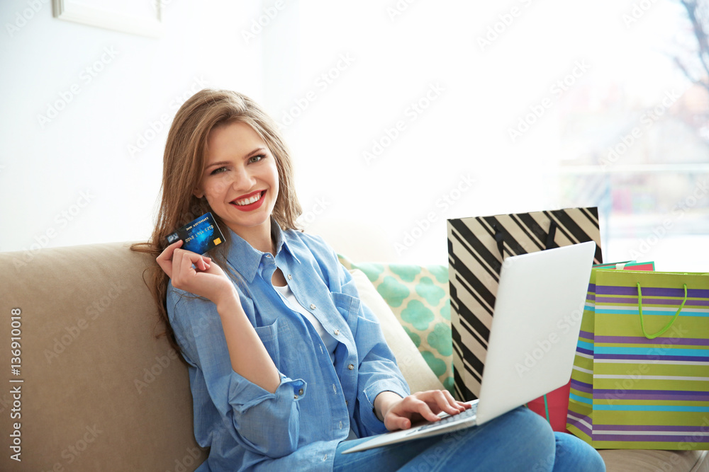 Beautiful young woman doing online shopping at home