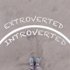 Wall Mural - Extroverted vs Introverted text on asphalt ground, feet and shoe