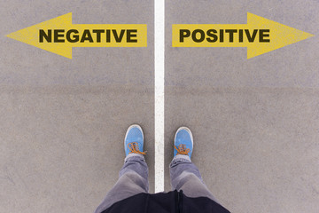 Wall Mural - Negative vs Positive text arrows on asphalt ground, feet and sho