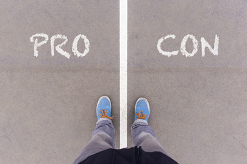 Wall Mural - Pro and Con text on asphalt ground, feet and shoes on floor