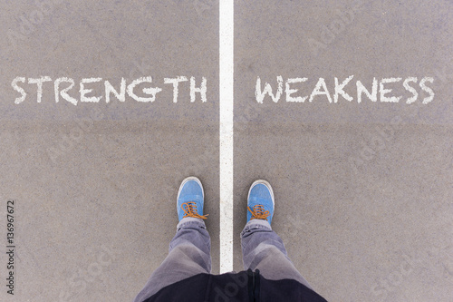Fotografía Strength and weakness text on asphalt ground, feet and shoes on