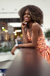 Attractive young afro american girl smiling and standing near handrail.