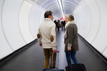 Wall Mural - Senior couple in hallway of subway pulling trolley luggage.