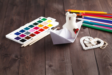 Paper boat and soft toy on wooden table