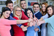 © FS-Stock - Cheerful group of students smiling at camera with thumbs up, success and learning concept
